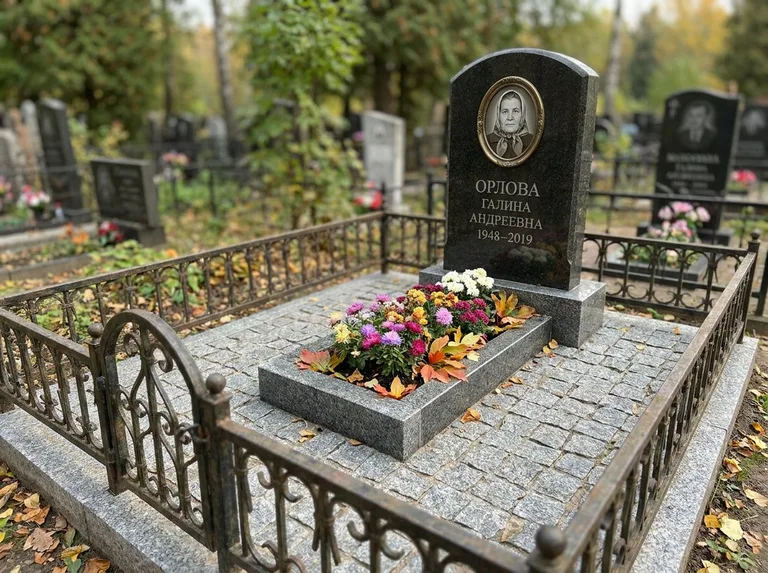 Благоустроенное захоронение с гранитной плиткой, оградой и цветником в Норильске