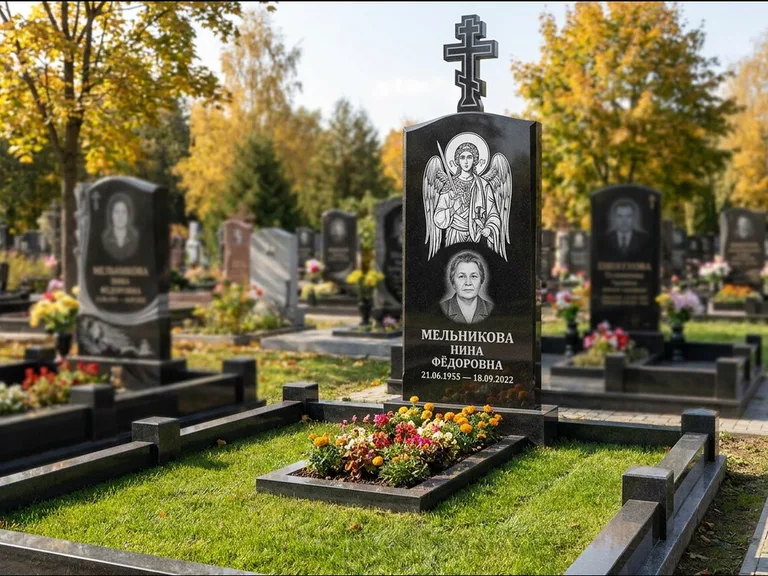 Памятник с гравировкой иконы: округлая стела-медальон с ликом — гравировка Богородицы «Семистрельная», луговые травы и полевые цветы за участком, работа «Гущин» в Норильске