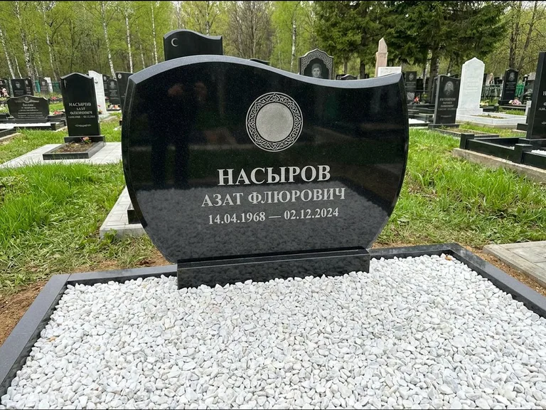 Мусульманский памятник: стела с волнообразным скошенным верхом — гравировка мечети под полумесяцем и звёздами, белая мраморная крошка с бордюром, работа «Насыров» в Норильске