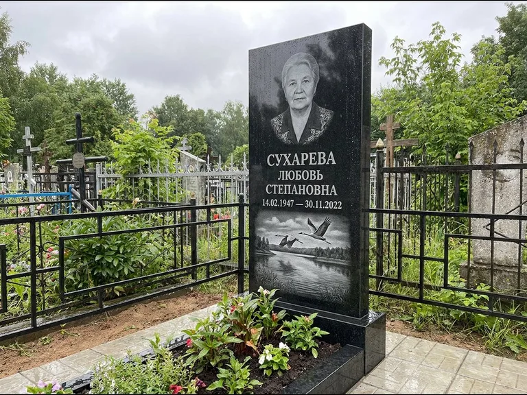 Памятник с гравировкой журавлей — гравировка пары журавлей над гладью озера в нижней части, работа «Сухарева» в Норильске