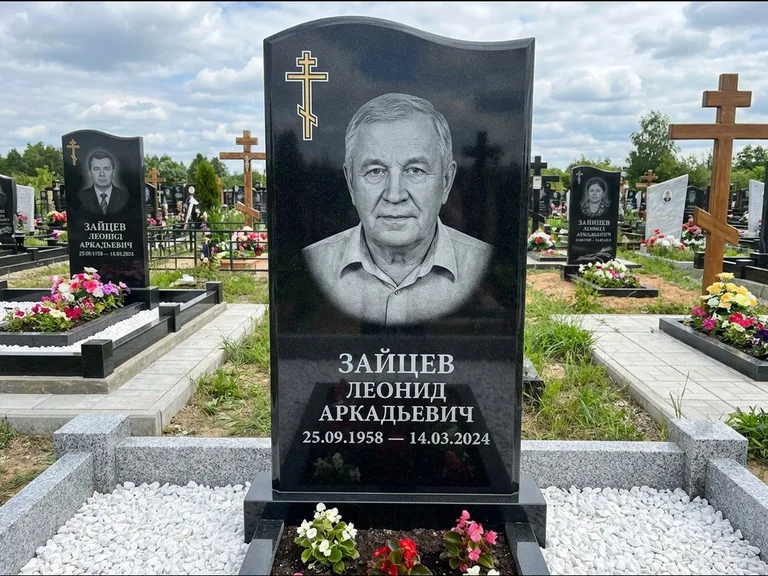 Памятник из чёрного гранита — горизонтальная семейная стела с аркой с процветшим крестом с виноградной лозой, работа «Верещагин» в Норильске