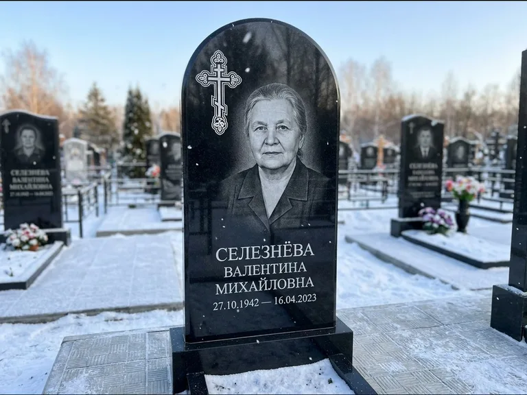 Памятник из чёрного гранита — массивная стела с крестом в лучах с крестом в лучах, работа «Одинцова» в Норильске