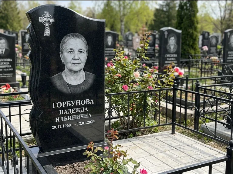Памятник из чёрного гранита — высокий обелиск с кельтским крестом, работа «Одинцова» в Норильске
